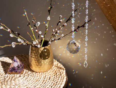 Selective focus on round ball shape crystal rainbow maker suncatcher hanging in home with Orgonite or Orgone pyramid. Good Feng Shui, Sha Chi reflection, energy flow concept.